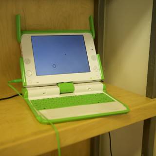 Green and White Laptop on Wooden Shelf