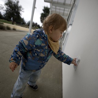 Young Child Exploring White Wall at Outdoor Location