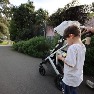 Young Boy with Snack by Stroller in Residential Area