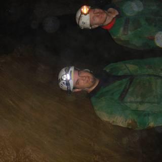 Two Men in Green Jackets Explore Natural Cave