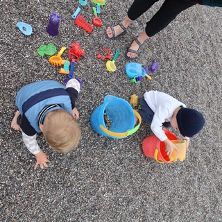 Children Playing with Beach Toys on Pebble Shore