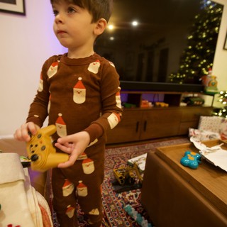 Young Child Opening Christmas Presents in Brown Santa Pajamas