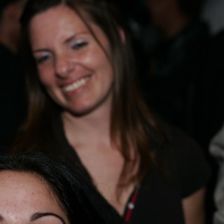 Woman Smiling Joyfully at Crowded Nighttime Event