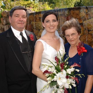 Bride Poses with Parents at Waterfall Wedding Venue