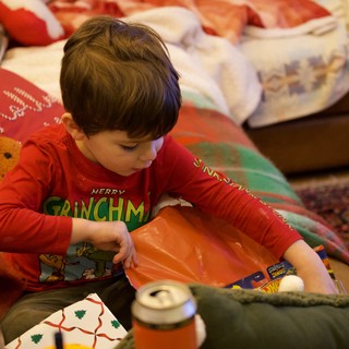Young Boy Opening Christmas Presents in Red Grinch Pajamas