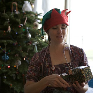 Holiday Elf Nurse Unwrapping Christmas Gift at Home