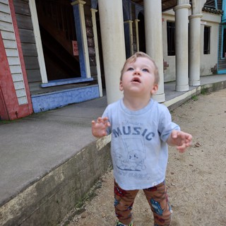 Young Child Looking Up in Wonder at Vintage Storefront