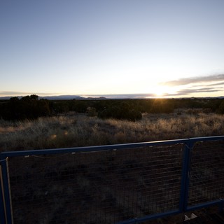 Sunset Over Desert Landscape with Metal Fence