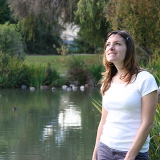 Young Woman Smiling by a Tranquil Park Pond