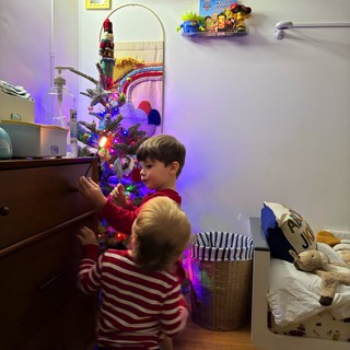 Brothers Decorating Christmas Tree Together in Bedroom