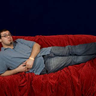 Man lounging on red velvet couch