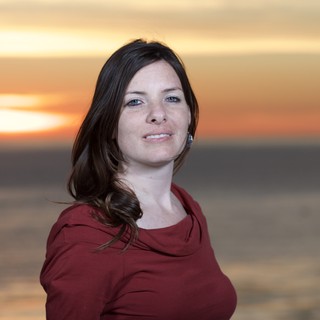 Woman Smiling Against a Golden Coastal Sunset