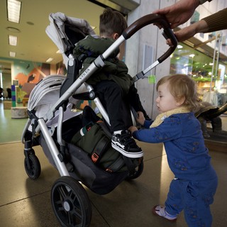 Toddler Helping Parent Push Stroller at Indoor Venue
