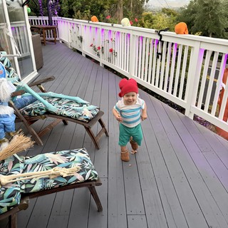 Joyful Toddler in Pink Hat Running on Decorated Deck