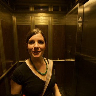 Woman Smiling in Vintage Wood-Paneled Elevator