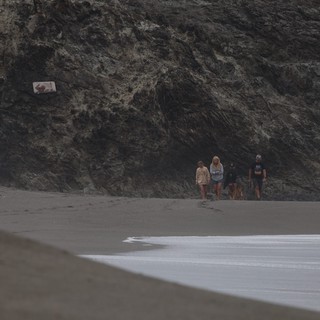 Beachwalkers Against Dramatic Dark Coastal Cliffs