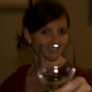 Woman Raising a Wine Glass in Dim Light