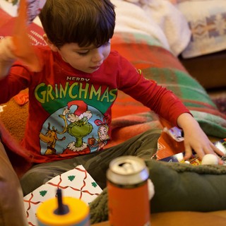 Child Opening Christmas Presents in Grinch Pajamas