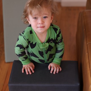 Toddler in Green Bat Pajamas on Ottoman