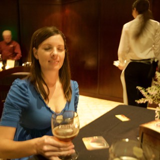 Woman Smiling Over Craft Beer at Evening Event