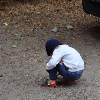 Young Boy Crouching in Curiosity on Dirt Path