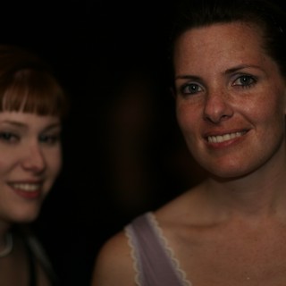 Two Women Smiling at a Dimly Lit Evening Event
