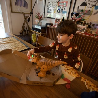Child Enjoying Pizza with Dinosaur Toy on Christmas