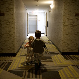 Two Children Walking Down Hotel Corridor at Dusk