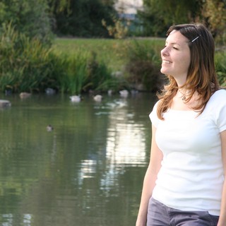 Joyful Woman Smiling by a Tranquil Park Pond