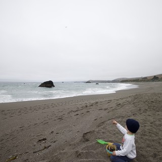 Child Points to the Sky on Misty California Beach
