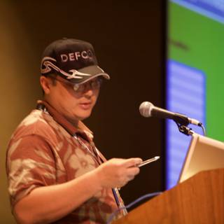 Hideaki Wakui delivering a speech wearing a baseball hat