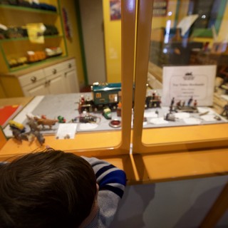 Child Examining Miniature Train Display at Museum