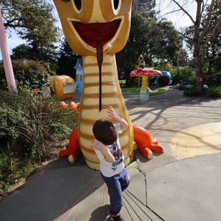 Child Exploring Whimsical Snake Sculpture in Theme Park