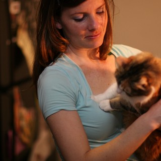 Woman Tenderly Holds Fluffy Cat in Warm Light