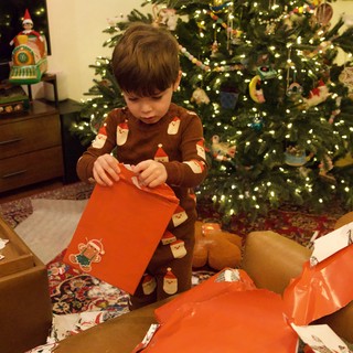 Young Boy Opening Christmas Gifts by Decorated Tree