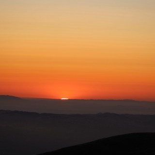 Last Light: Sun Sinking Behind Layered Mountain Ridges