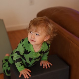 Toddler in Green Dinosaur Pajamas on Chair
