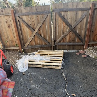 Weathered Wooden Gate with Wooden Pallet in Driveway