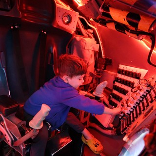 Young Explorer in Submarine Control Room Under Red Lights