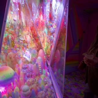 Vibrant Neon Claw Machine Display in Purple Arcade
