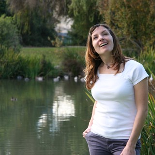 Joyful Woman Laughing by a Tranquil Park Pond