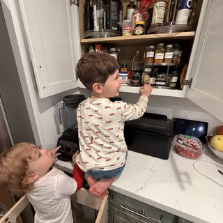 Siblings Working Together to Reach the Kitchen Cabinet