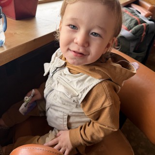 Joyful Toddler Smiling at Café Table