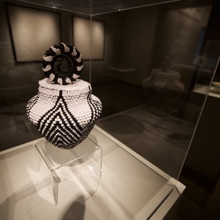 Traditional Beaded Vessel with Decorative Finial in Museum Display