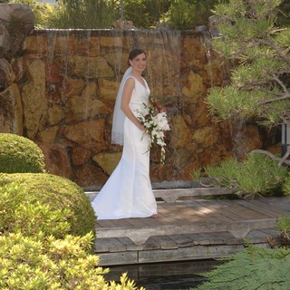 Bride Poses Before Stone Waterfall in Japanese Garden