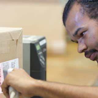 Curious Man Examining Barcode on Cardboard Box
