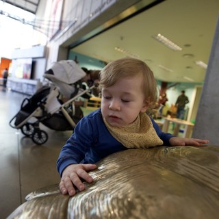 Young Child Exploring Bronze Sculpture at Museum