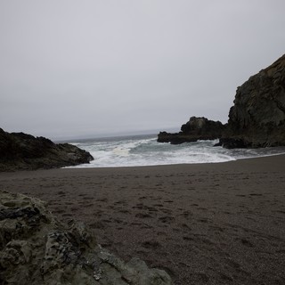 Rugged Cove Where Dark Sand Meets Crashing Pacific Waves