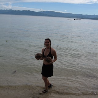 Smiling Woman Holding Coconuts on Fijian Shore