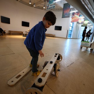 Child Exploring Interactive Wooden Balance Exhibit at Science Center